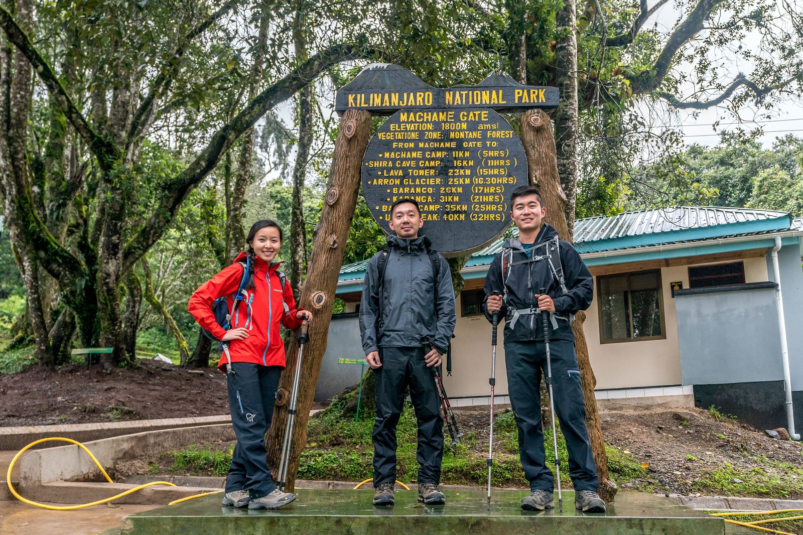 Grace, Jason, and James posing at the Machame Gate sign at the start of the Kilimanjaro climb
