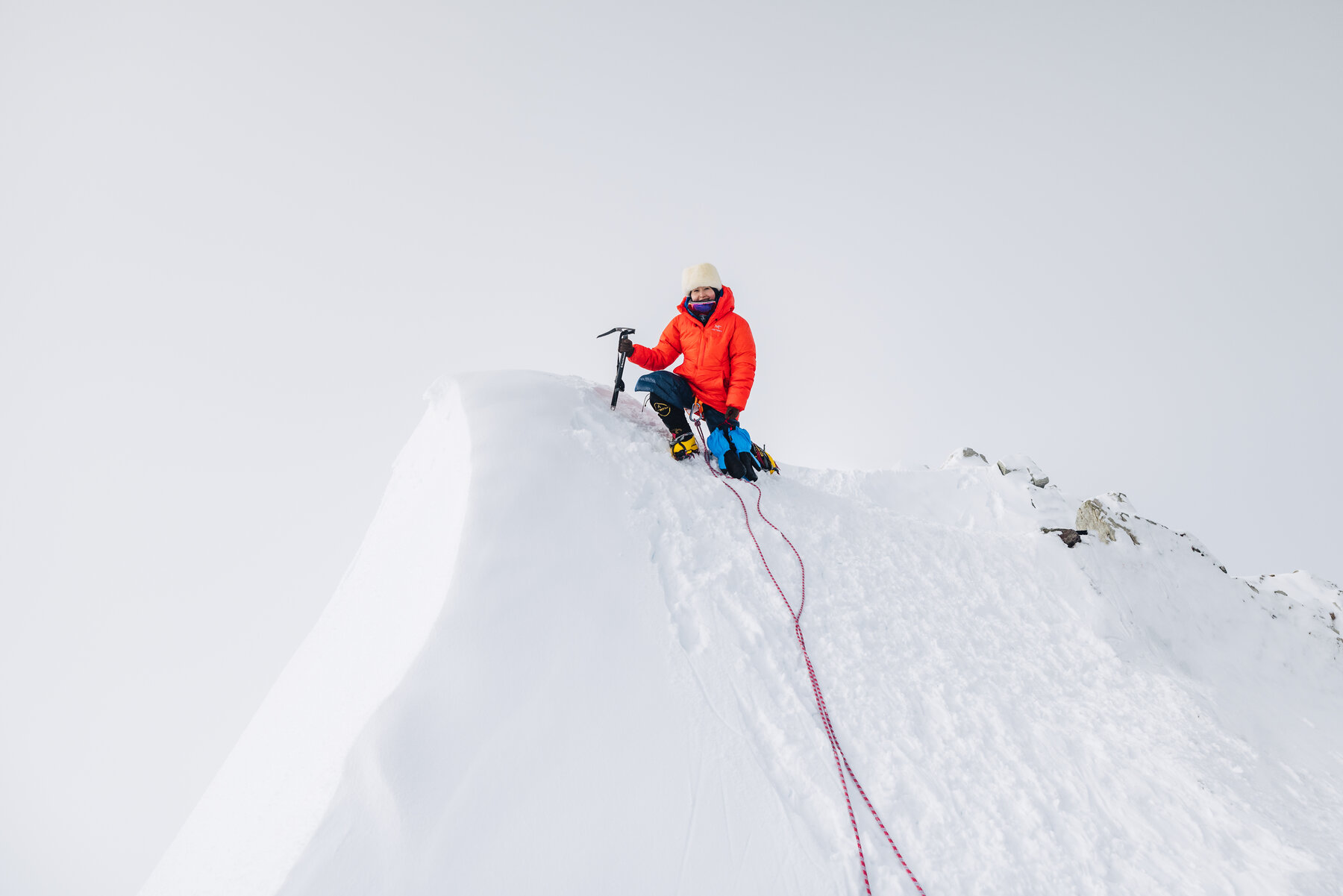 Grace sitting on the summit of Vinson with ice axe and climbing gear