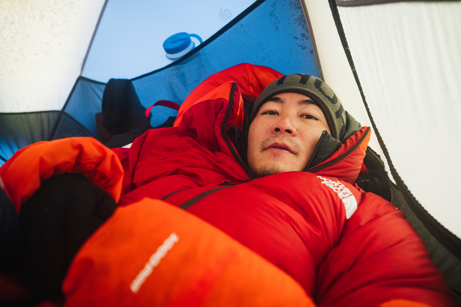 Jason lying in a red sleeping bag inside the tent at High Camp on Vinson