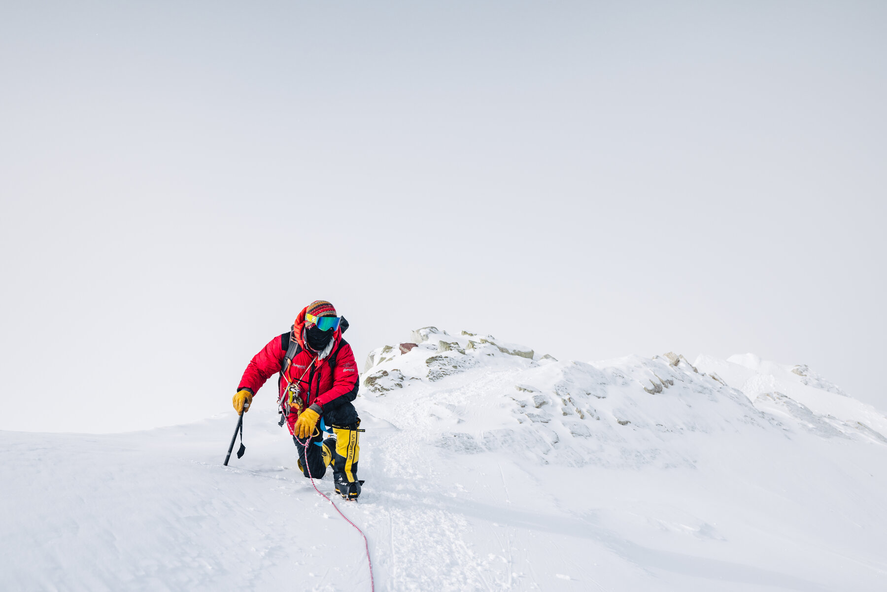 Climber scrambling along the rocky summit ridge of Vinson with ice axe