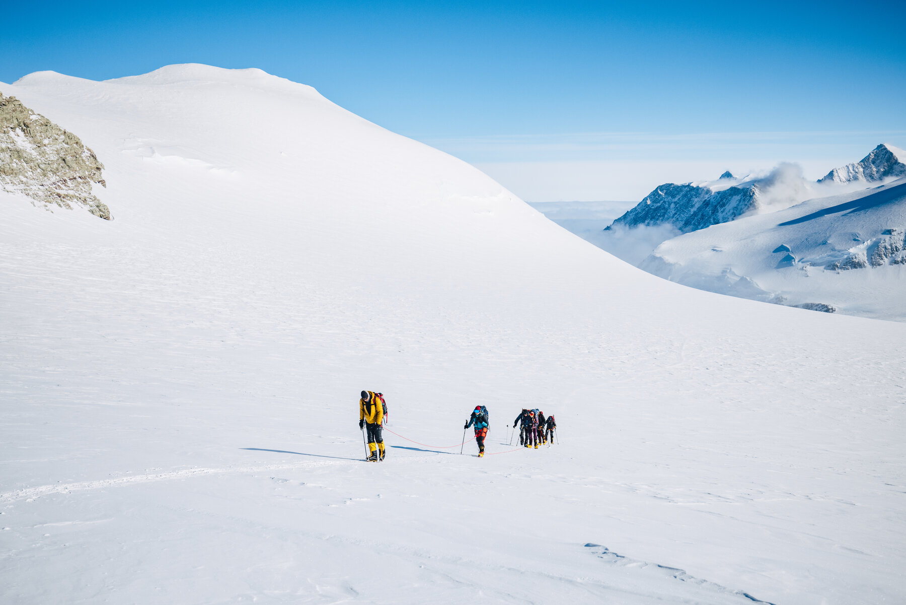 Team roped together ascending toward Vinson summit on clear day